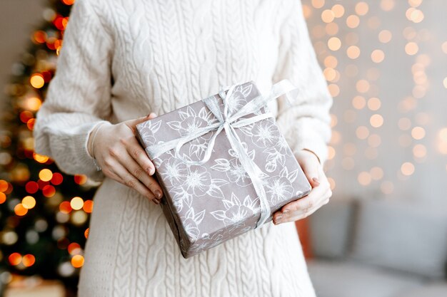 Girl holding a beautiful box with a Christmas gift closeup