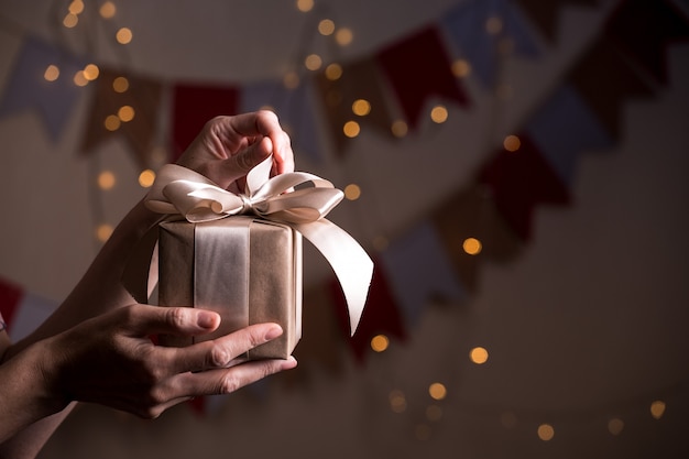 Girl holding beautiful  gift for the day valentines day. box and bow and bokeh in the background