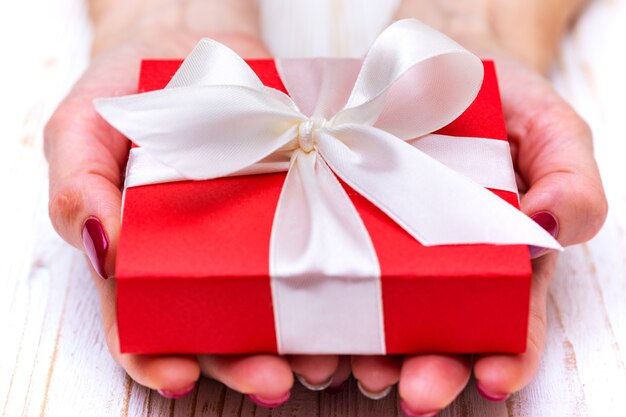 日バレンタインデーの美しい贈り物を保持している女の子。赤い箱と白い弓
