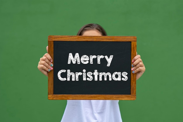 Girl holding a blackboard with the message happy christmas written