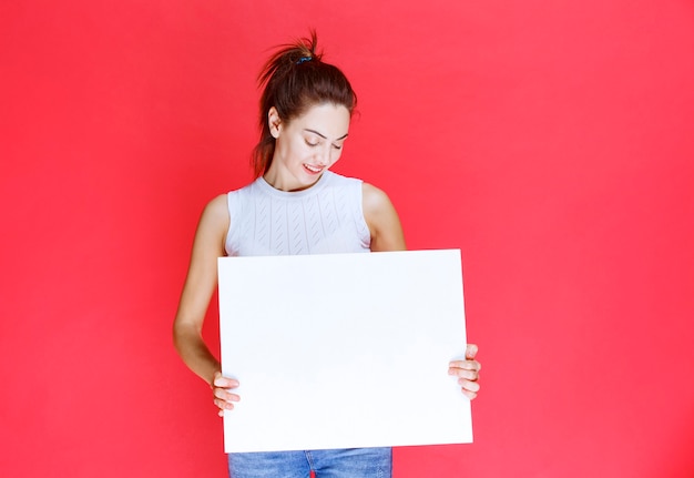 Girl holding a blank square ideaboard for brainstorming. 