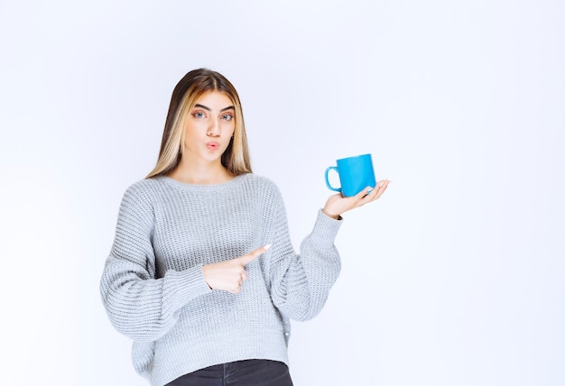 Girl holding a blue coffee mug and promoting it.
