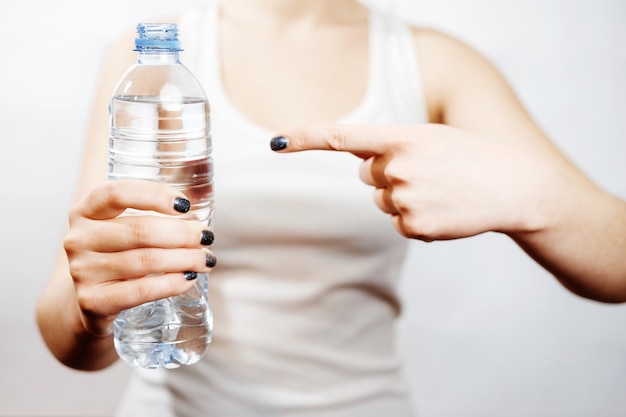 Girl holding a bottle of water in her hand, can not see the face, small bottle, White shirt, gesture super, finger points to the bottle, close-up