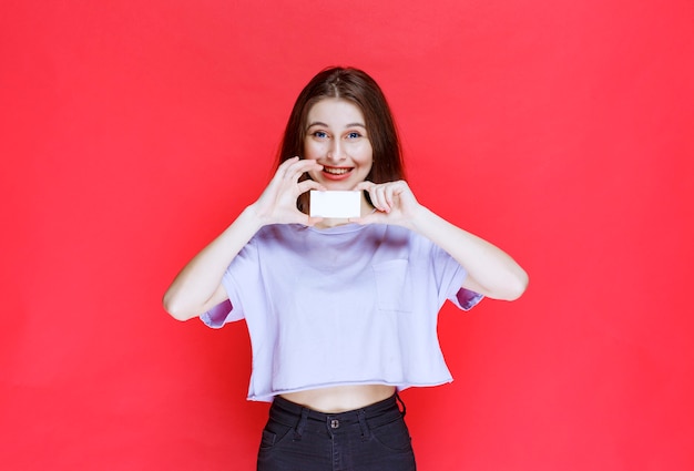 Girl holding a business card and looks happy. 