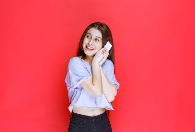 Ragazza in possesso di un biglietto da visita e sorridente.