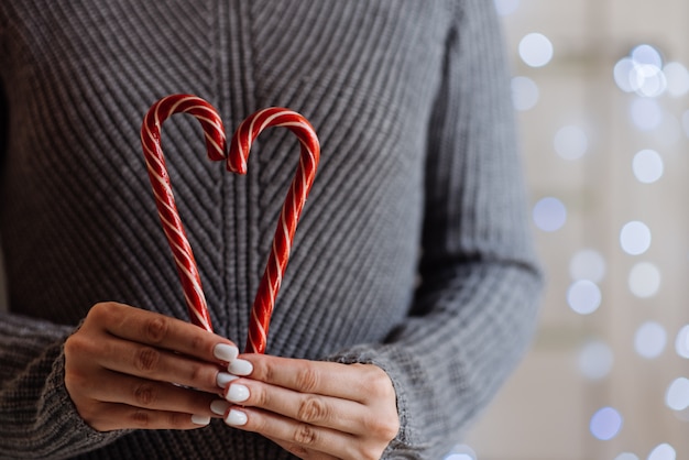 Girl holding cacao with whipped cream and peppermint candy cane. Christmas holiday.