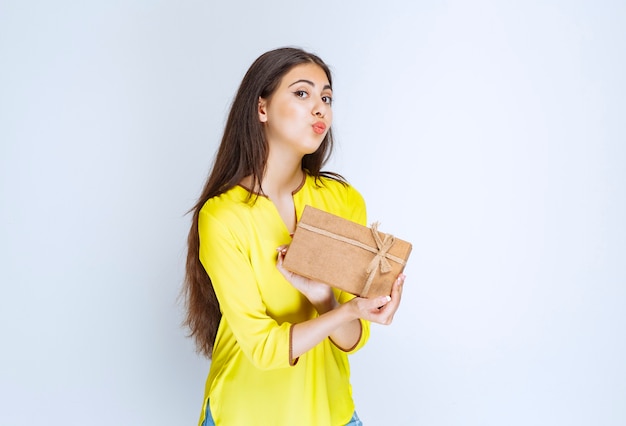 Ragazza in possesso di una confezione regalo di cartone e sentirsi positiva.