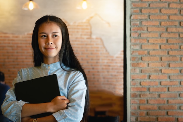 幸せでコンピュータの手帳を持っている少女。