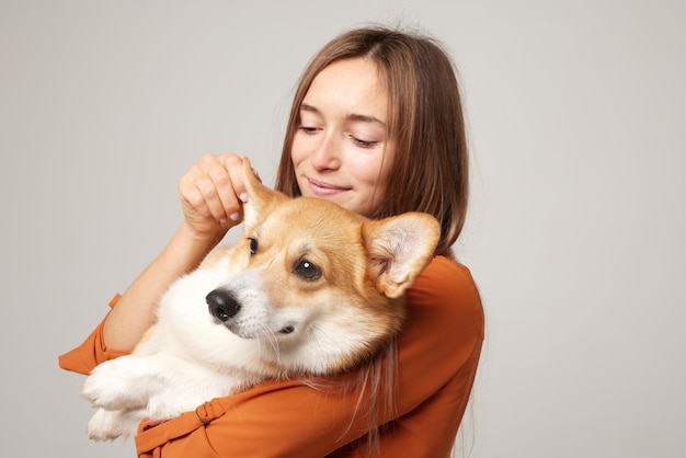 girl holding a corgi dog in her arms on a clean light background love for dogs