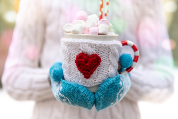 Girl holding the cup of cocoa in hands outdoor in winter