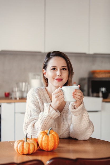 Girl holding a cup of coffee and sitting at table