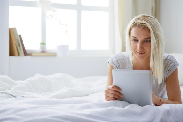 Girl holding digital tablet with blank screen and smiling at camera in bedroom