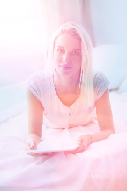 Girl holding digital tablet with blank screen and smiling at camera in bedroom