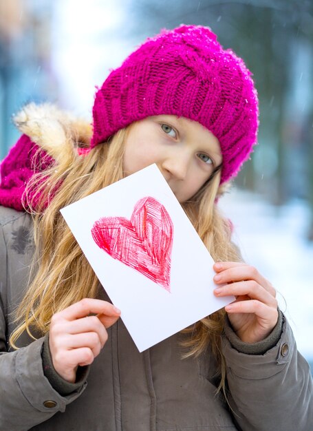 Girl holding drawing with a heart on the valentines day