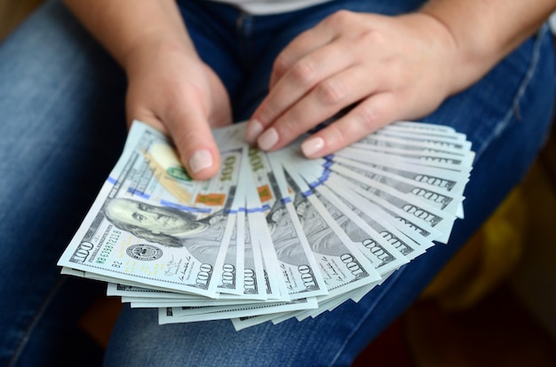 A girl holding a fan of dollar bills