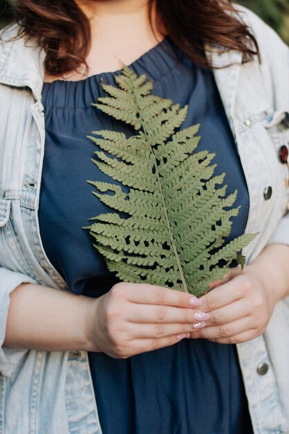 Photo girl holding a fern leaf in her hands spring nature green plants. spring