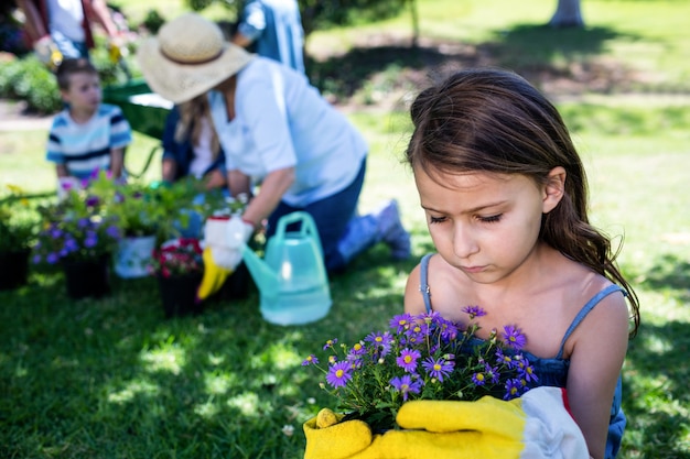 Foto ragazza che tiene un vaso di fiore mentre facendo il giardinaggio con la famiglia