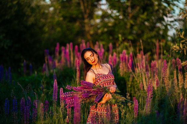 Girl holding flowers. Brunette in field. sunset