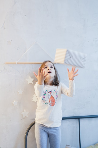 Photo girl holding gift for new year or christmas, christmas tree and interior decorated for new year, christmas, holiday anticipation