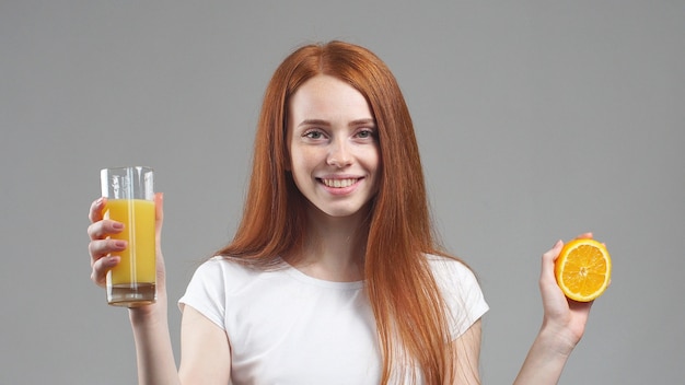 Girl holding a glass of orange juice and orange