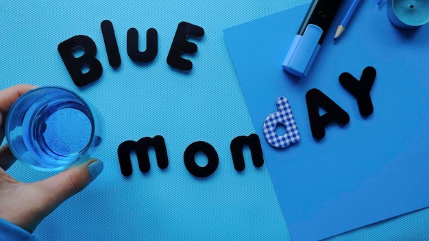 Girl holding a glass with blue drink on a blue background with Blue Monday lettering