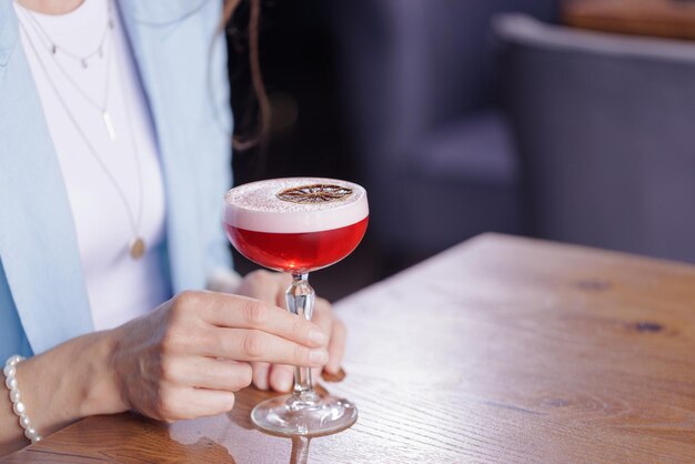 Ragazza che tiene un bicchiere con un cocktail in un concetto di ristorante primo piano bar o ristorante