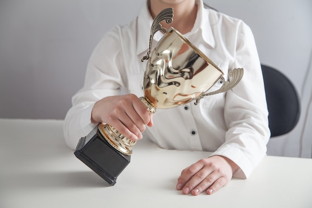 Ragazza con trofeo d'oro in ufficio. affari, successo