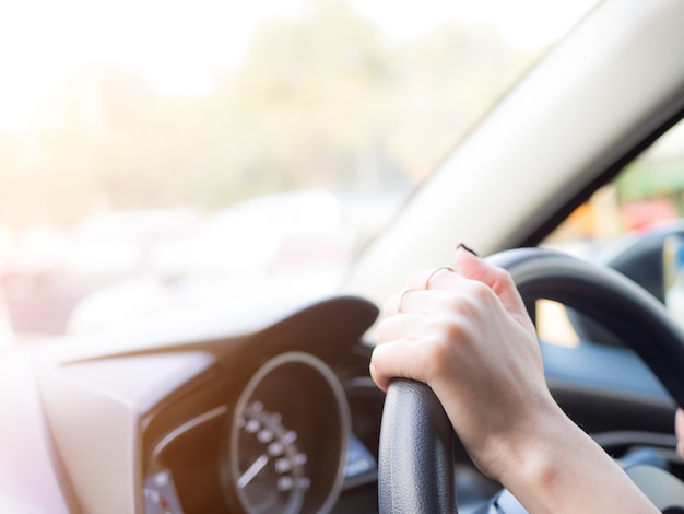 Girl holding hand on wheel to handle the car,