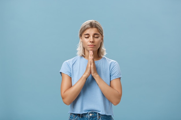 Фото Девушка, взявшись за руки в молитве, загадывая желание, надеясь, что бог слышит ее молитвы с закрытыми глазами