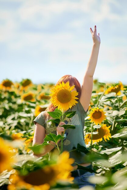 Girl holding a hat in sunflowers