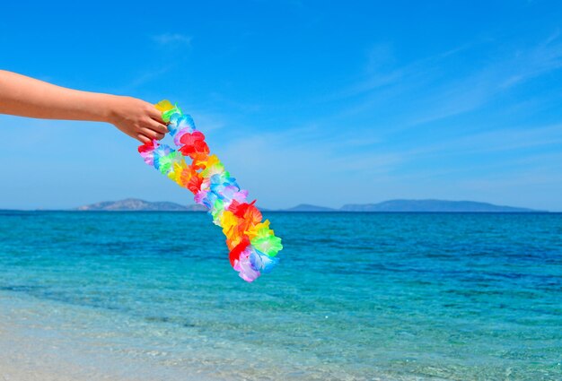 Girl holding a hawaiian necklace by a tropical shore