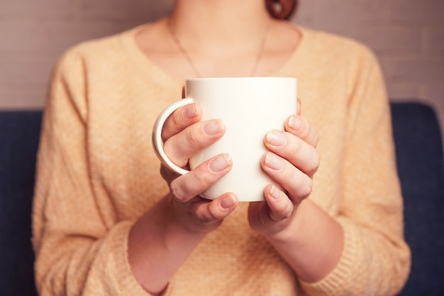 a girl holding in her hands a mug of coffee