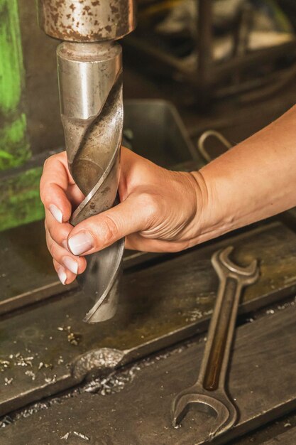 Foto ragazza che tiene un enorme trapano in fabbrica