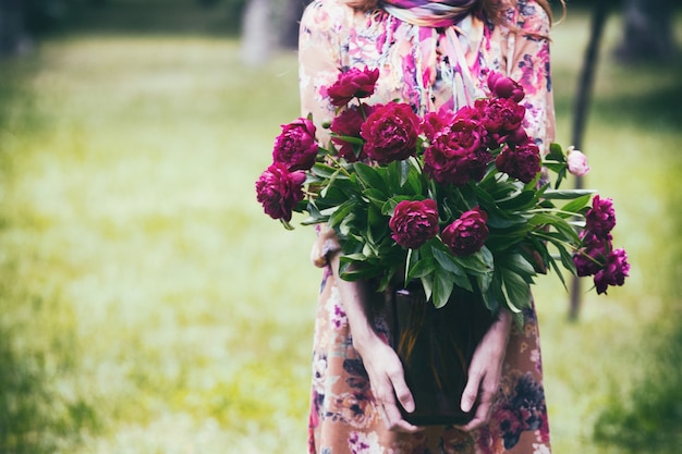 Girl holding a jar with a bouquet of peonies