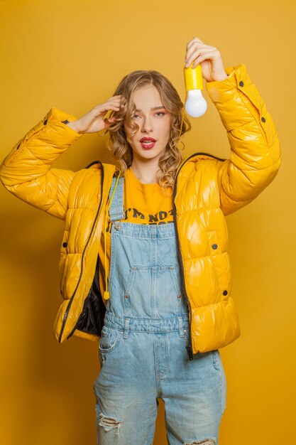 Girl holding lightbulb on yellow background