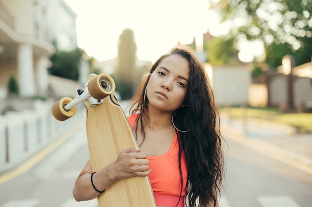 Girl holding a longboard in her hands