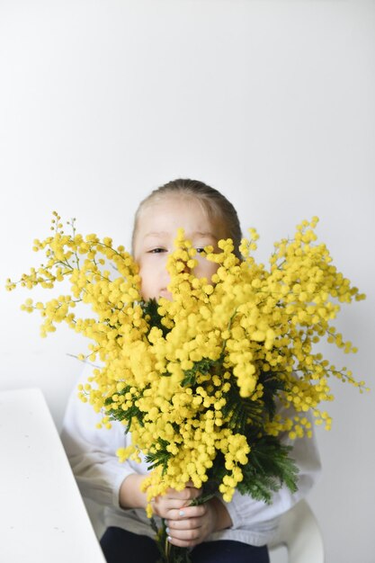 Girl holding mimosa on a white wall background