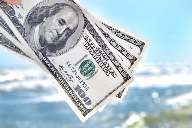 Girl holding money bill of 300 dollars on background of sea ocean