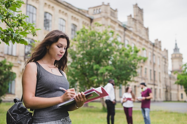 Photo girl holding notebook writing standing outside