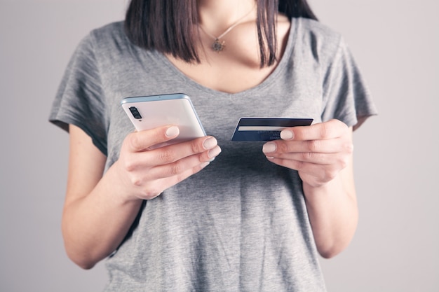 Girl holding a phone and a bank card in her hands