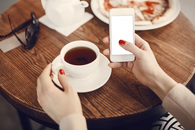 Girl holding phone with empty screen at cafe