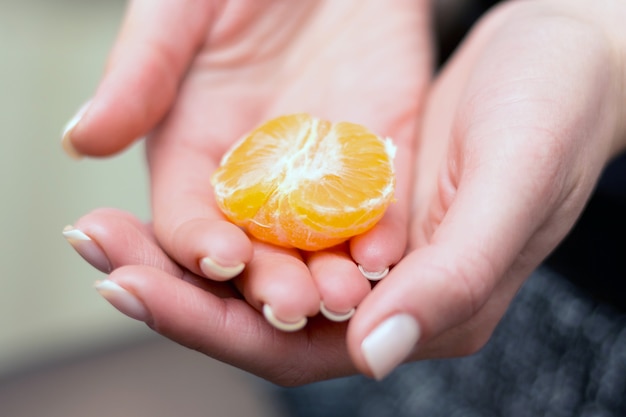 Girl holding a piece of mandarin in her hands