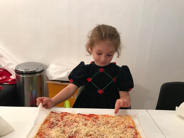 Foto ragazza che tiene la pizza sul tavolo a casa