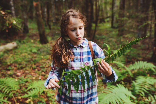 Photo girl holding plant while standing in forest