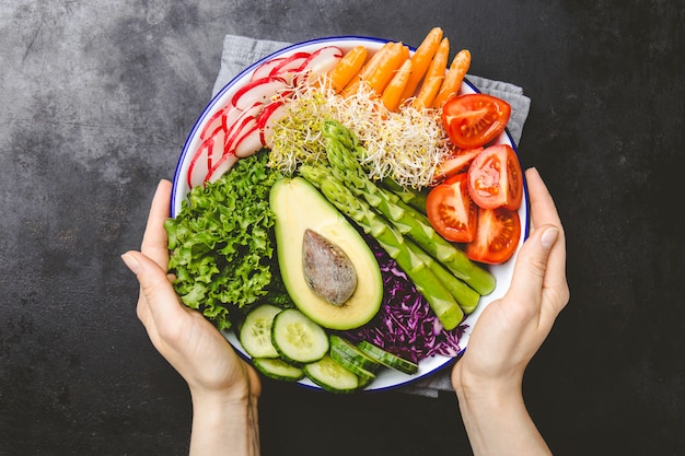 Photo girl holding plate with fresh vegetables