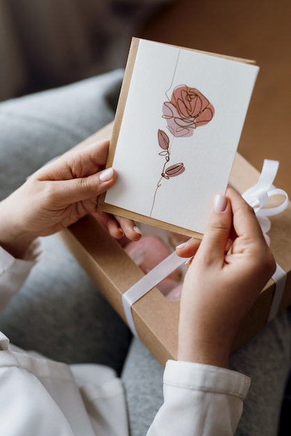 Ragazza con in mano una cartolina con un fiore dipinto