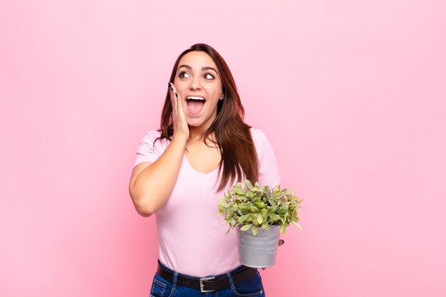 幸せと興奮を感じて鉢植えの植物を保持している女の子