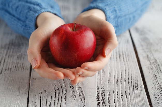 Девушка держит красное яблоко в руке