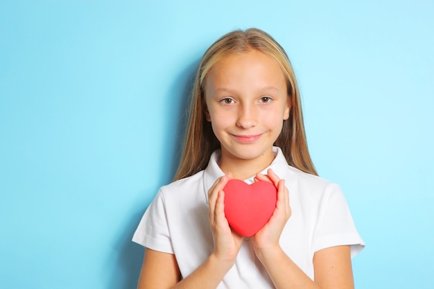 Girl holding a red heart in her hands on a blue background