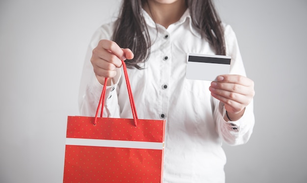 Ragazza che tiene il sacchetto della spesa con carta di credito. shopping